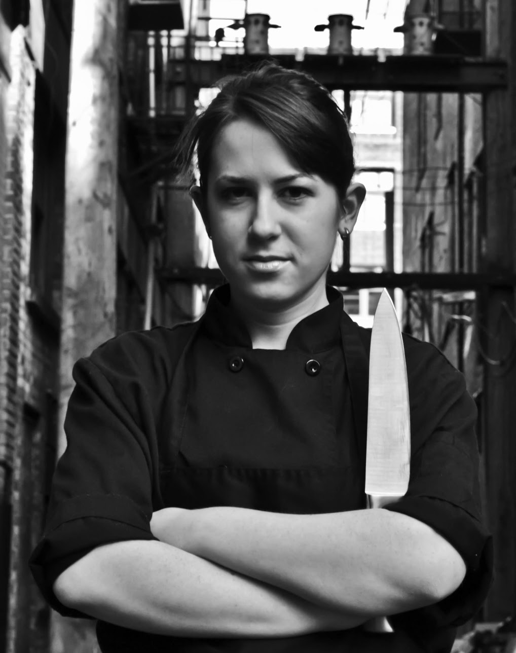 Leah in chef’s attire, holding a kitchen knife